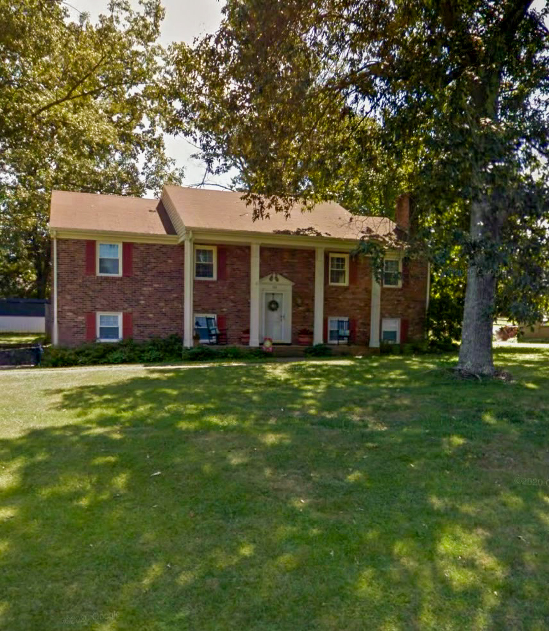 Brick split‑level house with red shutters, white front door, and large trees casting shade over the front lawn belonging to Sponsored Residential Providers Takeyshia Gibson and Antonio Carter in Forest, Virginia.