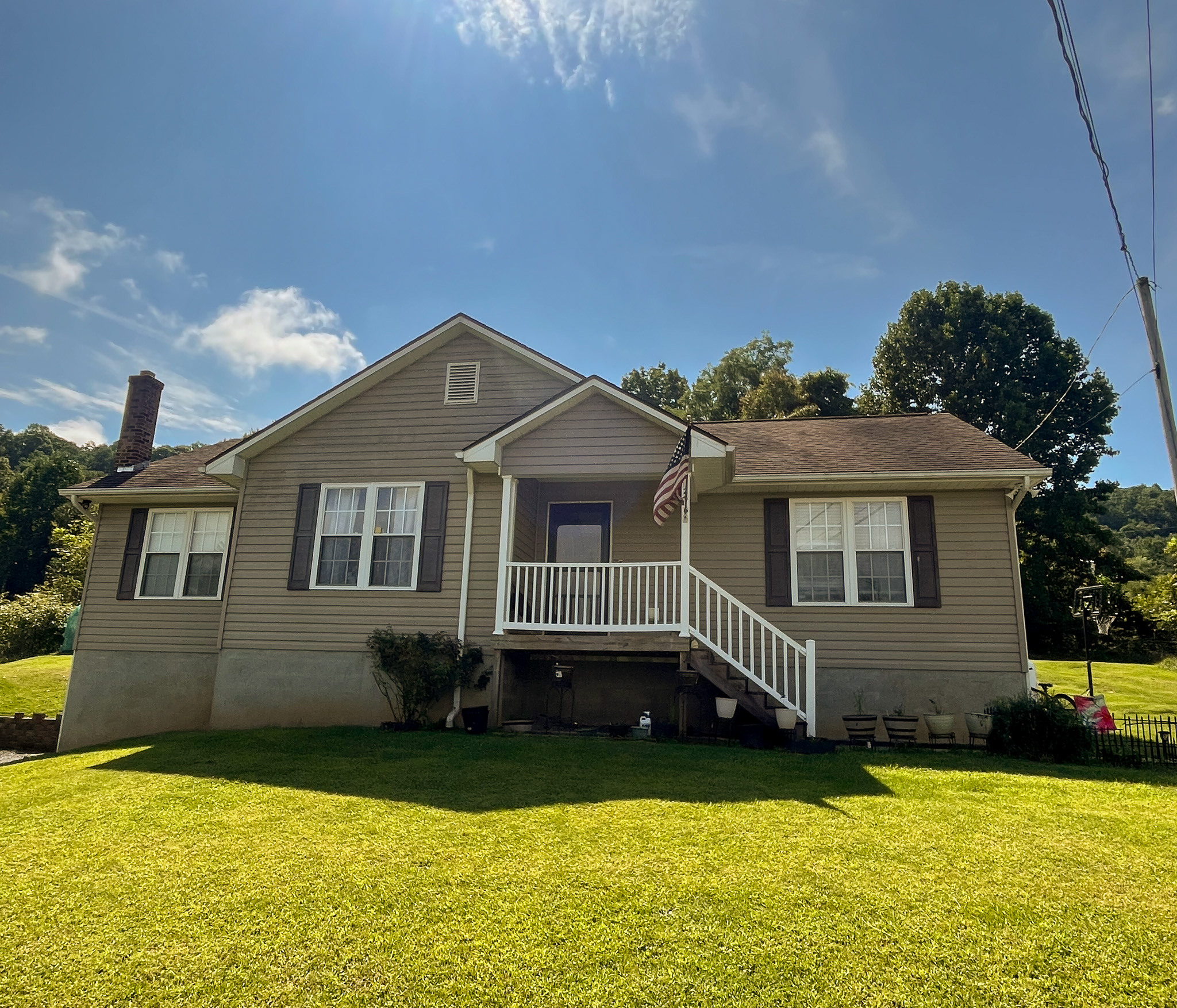 Front view of a single-story home with a covered porch, front steps, and a large grassy yard under a blue sky. This is the home of Sponsored Residential Provider Delmy Sexton in Woodlawn, VA.