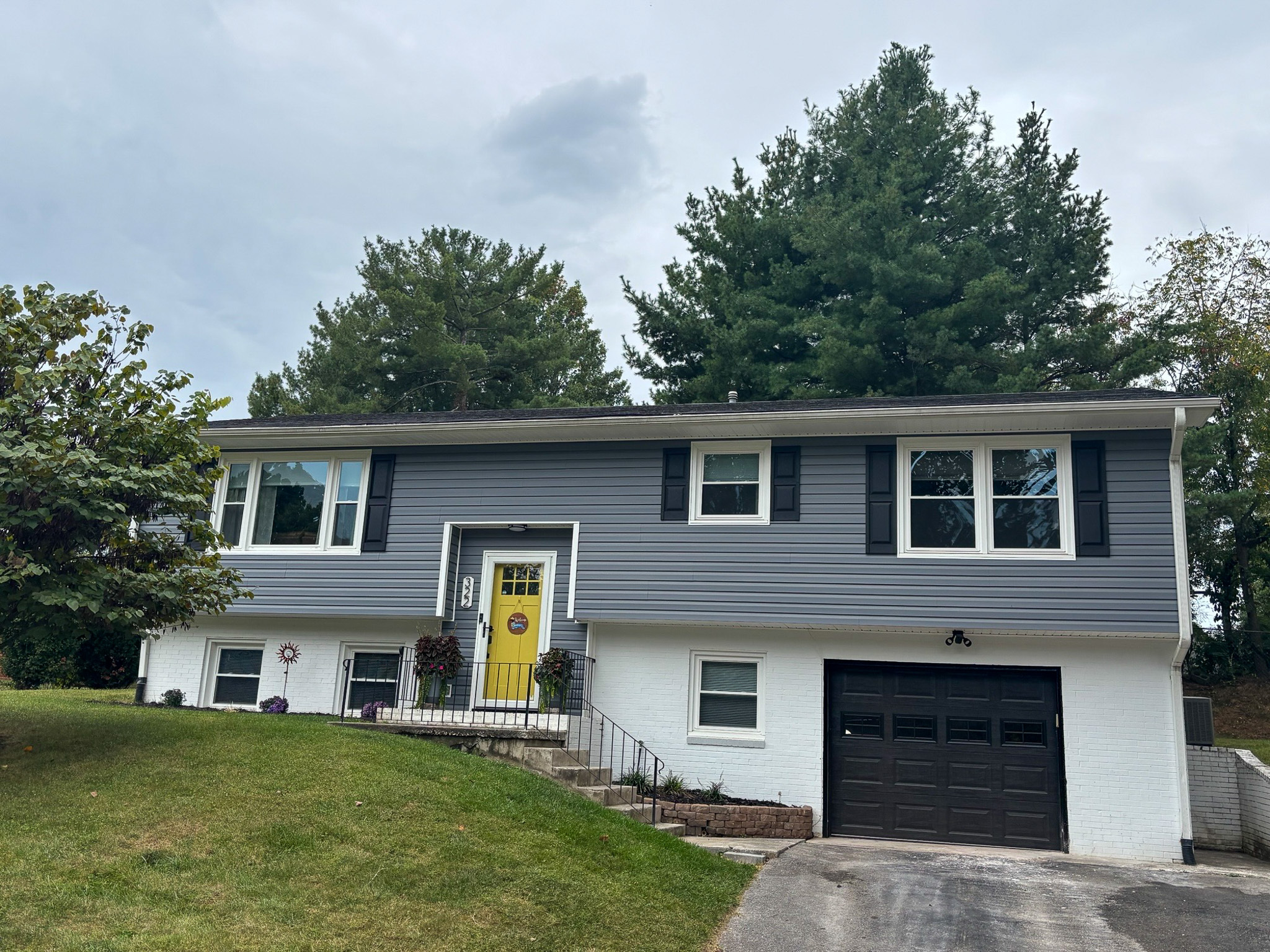 A split‑level house with gray siding, a yellow front door, and an attached garage on a sloped lawn belonging to Sponsored Residential Providers Hadassah Hawks and Antonio Hernandez in Salem, Virginia.