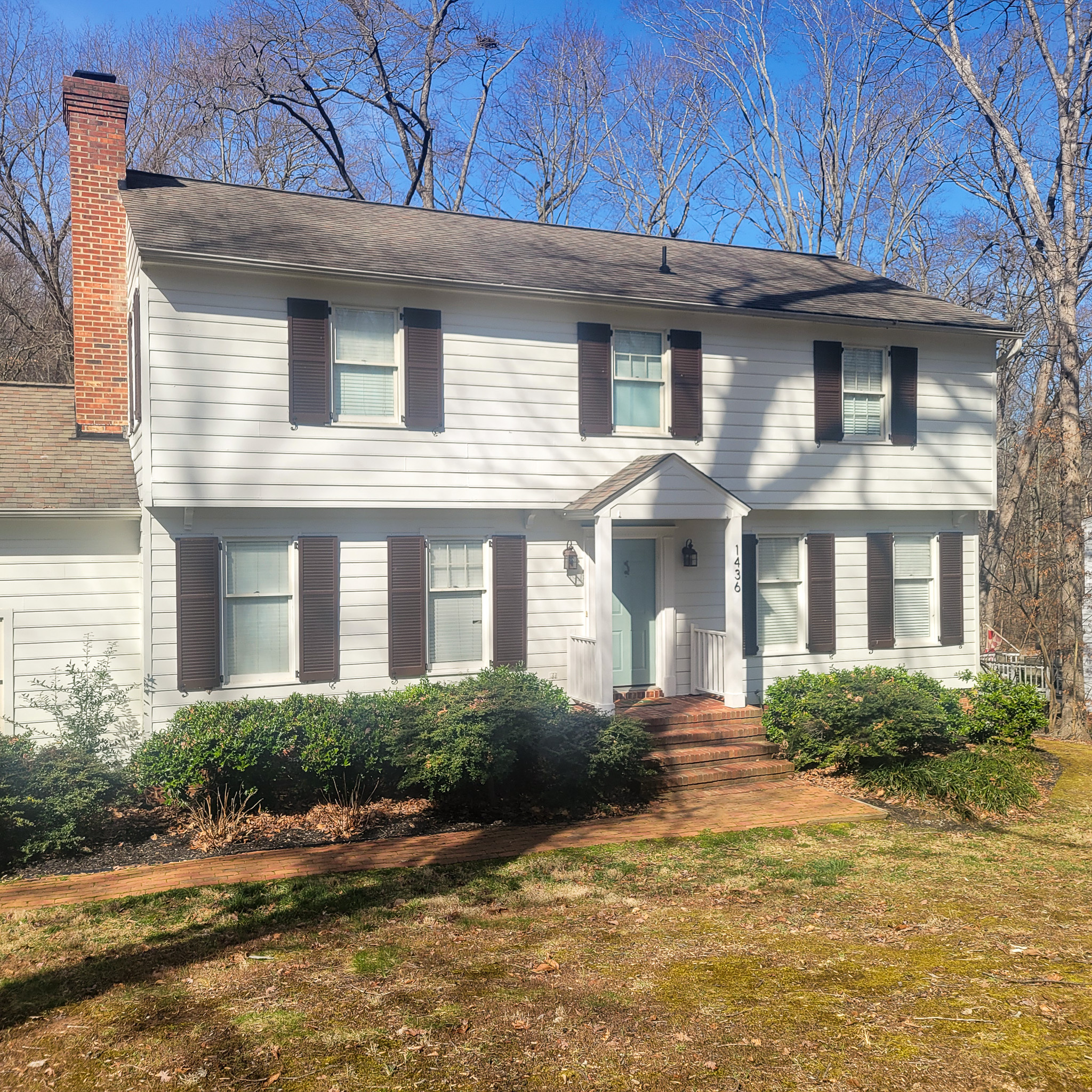 Two‑story white house with dark shutters, a brick chimney, and a small portico over the front door belonging to Group Home Provider Jared Nepal in Fredericksburg, Virginia.