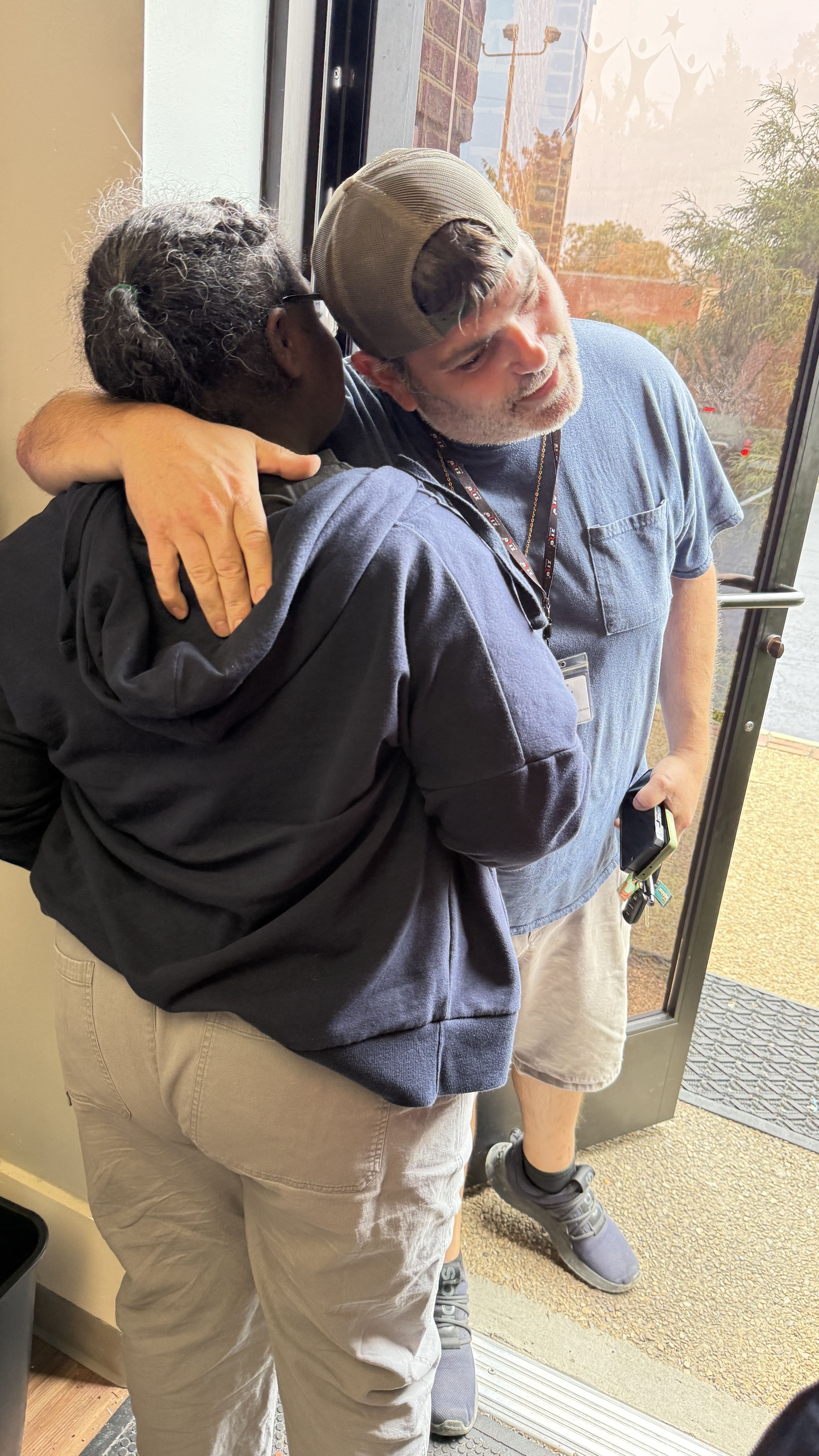 Wall Connections driver hugs a woman he is picking up to drive home from a Wall Star Center day support program when she rushes to door to greet him.