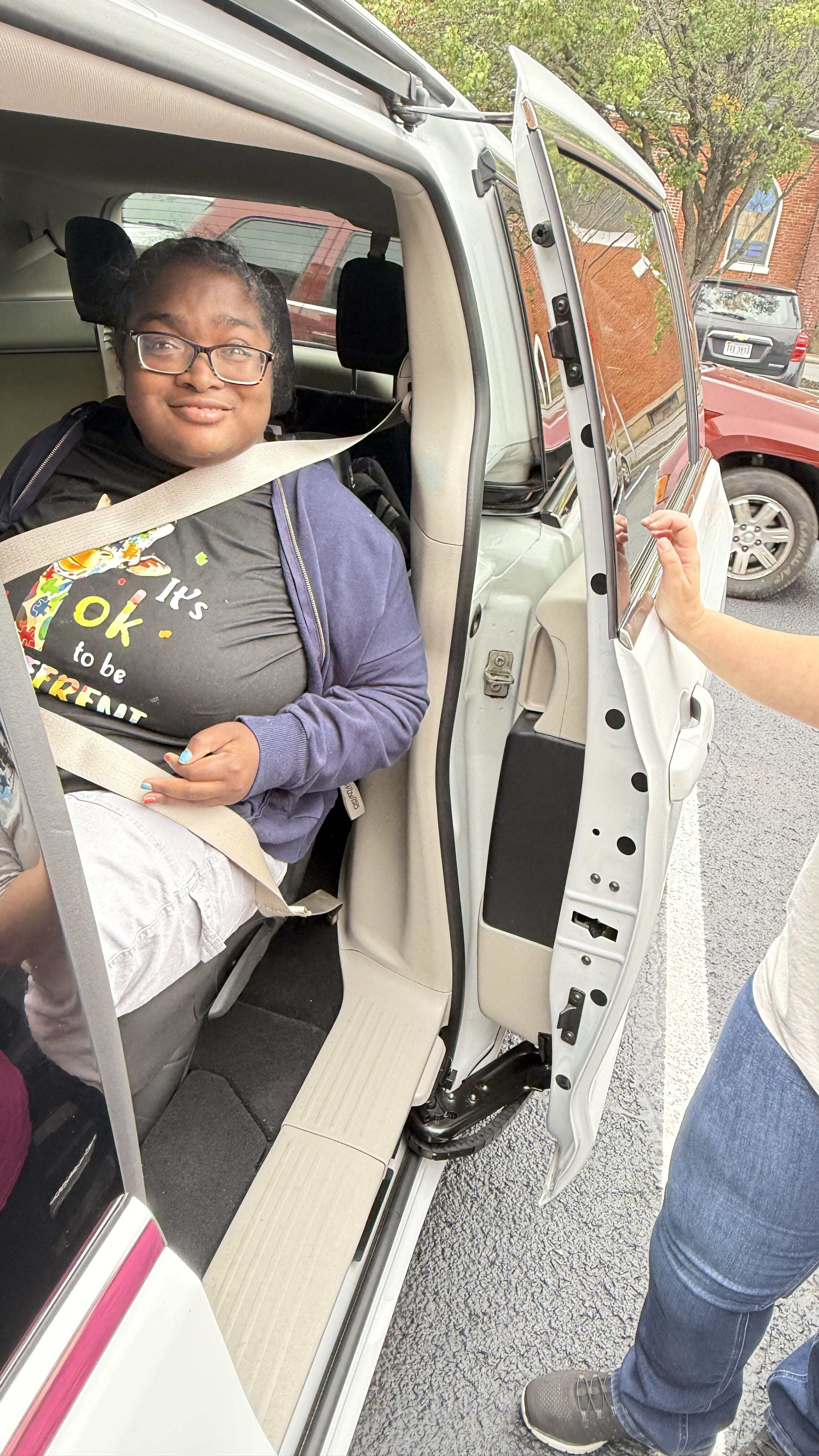 Woman wearing a seatbelt smiles while sitting in a minivan with the door open